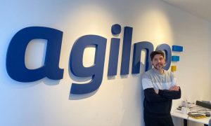 Ivan Car, Fullstack Developer at Agilno, in the office in front of Agilno logo.